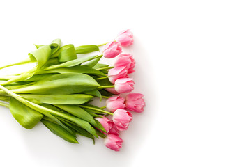 pink tulips lie on a white table next to colored pens