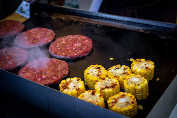Tasty grilled corns and burgers. large grill yellow corn cut into small slices. The process of cooking vegetables on the grill.
