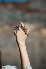 Close up photo of female hands with handmade jewellery,  rings, necklace, bracelet. Outdoors photo with lake in background.