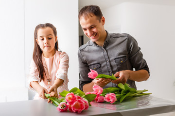 Cute little girl and her handsome father. Father makes bouquet flowers his little daughter.