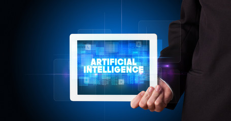 Young business person working on tablet and shows the inscription: ARTIFICIAL INTELLIGENCE