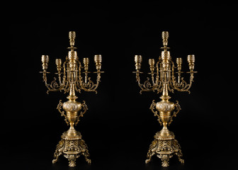 two classic bronze chandeliers on a black background, ancient candlesticks studio photo, antique...