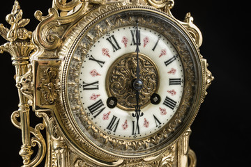 Fototapeta na wymiar dial of vintage bronze clock on black background, antique clock photo close up, old bronze clock in gilding, six o'clock on the dial