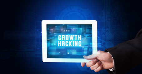 Young business person working on tablet and shows the digital sign: GROWTH HACKING