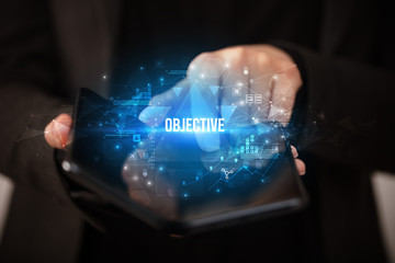 Businessman holding a foldable smartphone with OBJECTIVE inscription, business concept
