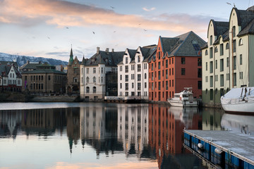 Fototapeta na wymiar A sunset photograph of beautiful buildings reflecting off the water, taken in Aalesund, Norway.