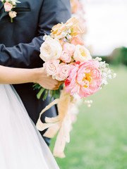 Beautiful wedding bouquet in hands of the bride. Just married wedding couple posing and bride holding in hands bouquet