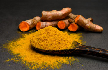 Turmeric powder and fresh turmeric (curcumin) on black background ,Used for cooking and as herbal...