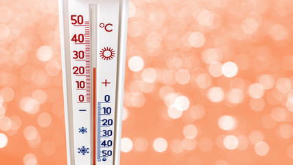 Thermometer on abstract orange background with bokeh shows plus 25 degrees, summer heat_