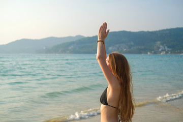 A young woman is practicing yoga on the ocean.