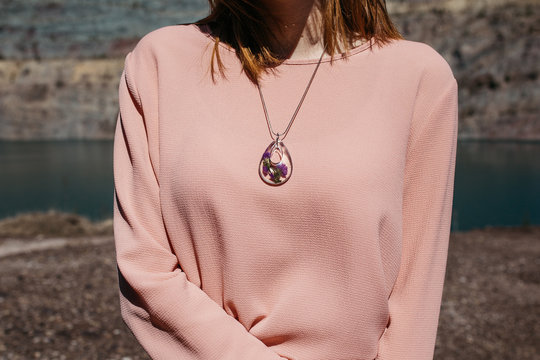 Close Up Photo Of Unrecognisable Model Woman Wearing Purple Necklace And Pink Shirt.  