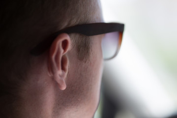 a part of a person’s face with glasses is driving