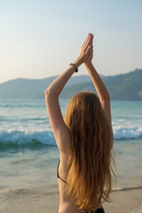 A young woman is practicing yoga on the ocean.
