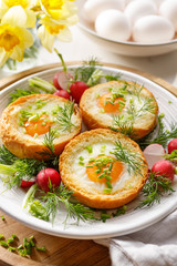Spring breakfast eggs baked in rolls with the addition of fresh herbs and radishes, close up
