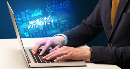 Businessman working on laptop with MARKETING AUTOMATION inscription, cyber technology concept