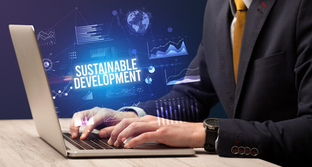 Businessman working on laptop with SUSTAINABLE DEVELOPMENT inscription, new business concept