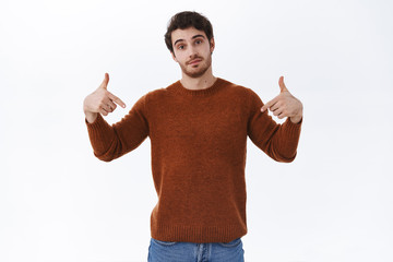 Fototapeta premium Cool and confident handsome bearded man pointing fingers down and look assured camera, recommend event tickets, promotion of store or corporate banner, advertisement concept, white background