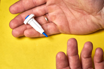 A diabetic checks his blood sugar. Close up man hands self-tested with a Lancet and a glucometer at home.