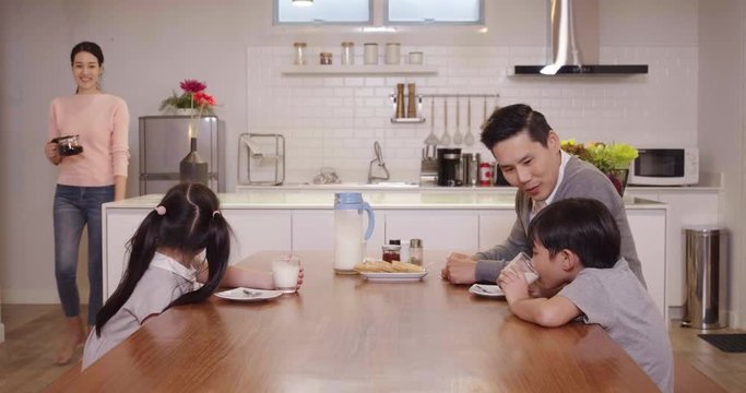 Happy family enjoy breakfast together. Cheerful young asian parents and cute small kids enjoy breakfast together on dining table at home. wonderful moment family concept 4k footage.
