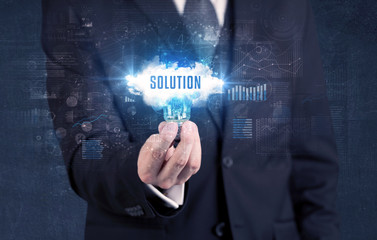 Businessman holding a light bulb with SOLUTION inscription, new business concept