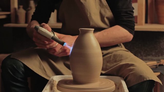 Ceramic art. Pottery hobby. Man hands using propane torch for glazing clay vase at studio.