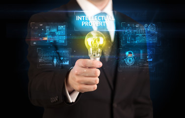 Businessman holding lightbulb with INTELLECTUAL PROPERTY inscription, online security idea concept
