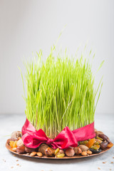 Happy Nowruz holiday background. Celebrating  various dried fruits, nuts, seeds, light background with green grass wheat, copy space top view