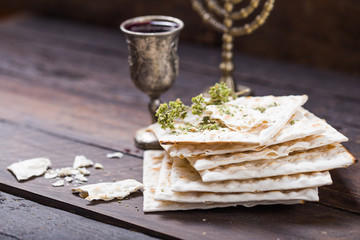 Red kosher wine with a white  matzah or matza on a vintage wood background presented as a Passover...