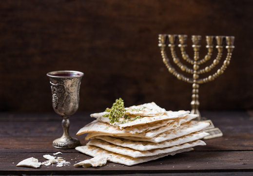 Red kosher wine with a white  matzah or matza on a vintage wood background presented as a Passover seder meal with copy space.