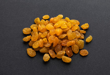 Fototapeta na wymiar Dried yellow raisins on black background
