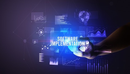 Hand touching SOFTWARE IMPLEMENTATION inscription, new business technology concept