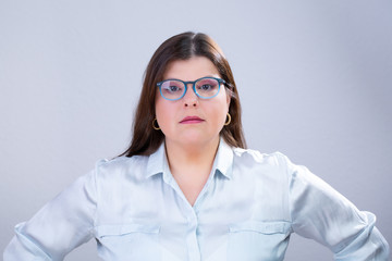 Business Woman Poses for a Studio Portrait, She is in a frontal position, serious and looking directly at the camera.