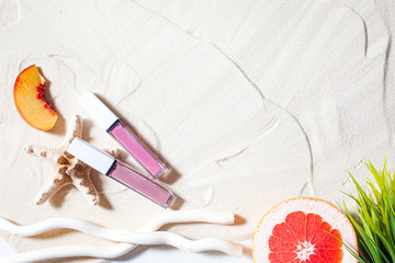 Wonderful beach. Lipstick, lip gloss, lip balm lie on the sand, surrounded by juicy fruits,...