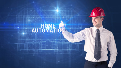 Handsome architect with helmet drawing HOME AUTOMATION inscription, new technology concept