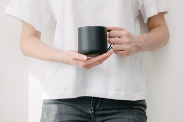 Black metal cup for tea and coffee in woman hand over white background for cup or mug mock up