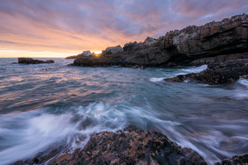 Fototapeta na wymiar A beautiful golden seascape photographed on a stormy day at sunset in Hermanus, South Africa.
