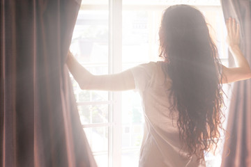 Woman opens the curtains in the morning