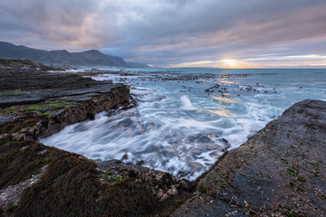Fototapeta na wymiar A beautiful early morning seascape photographed on a stormy day at sunrise in Hermanus, South Africa.