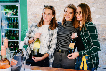 Young girls of family of winemakers selling bottles of wine and street market