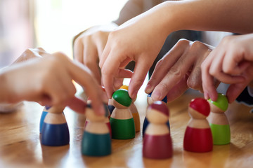 People choosing and picking up wooden figure from a group on the table