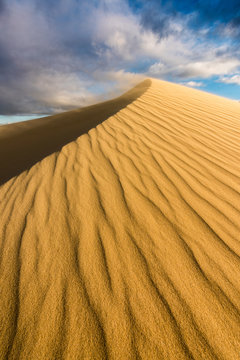 A dramatic vertical dune landscape taken on a cloudy stormy afternoon in Arniston, South Africa. The sand on the top of the peak was being blown by the strong wind.