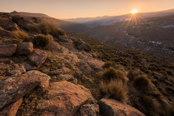 A tranquil snow-covered mountain landscape taken in Lesotho, with a golden sunset in the background.