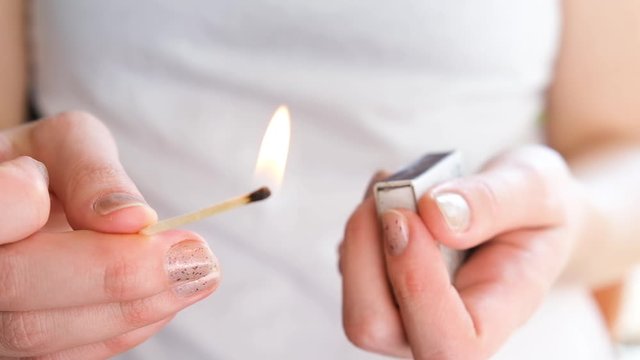 Female hand lighting match, close up.