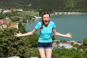 A girl in a blue t- shirt on a mountain. Lake view