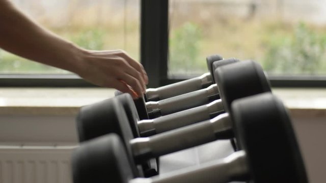 Strong male hand puts on a support a big dumbbell.