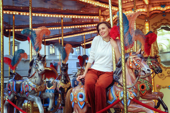 Woman riding on a traditional vintage carousel in a city park