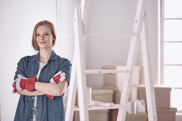 Beautiful young woman on a white wooden stepladder. Ready to repair the room. Women housework concept