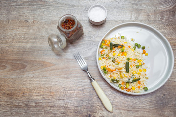 Risotto with vegetables and spices  served on gray plate with fork. Rustic food wooden background. top view, copy space