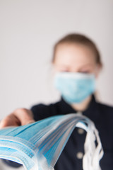 Person wearing blue medical mask and dark shirt holding some medical masks meant to prevent corona...