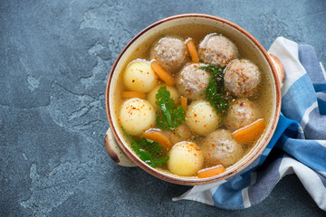 Beige bowl with meatball and potato soup, above view on a blue stone background with copy space